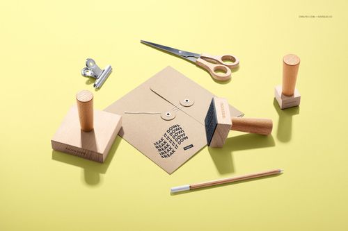 Set of wooden stamps, envelope, scissors, and pencil displayed on a yellow background in a stationery mockup.