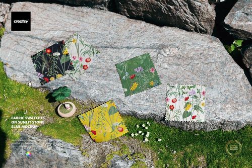PSD mockup of patterned fabric samples laid out on a large stone slab outdoors, surrounded by moss and grass.