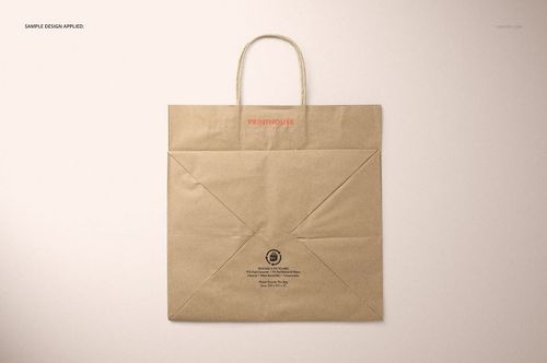 Front view of a natural kraft shopping bag mockup with twisted paper handles, displayed on a light surface.