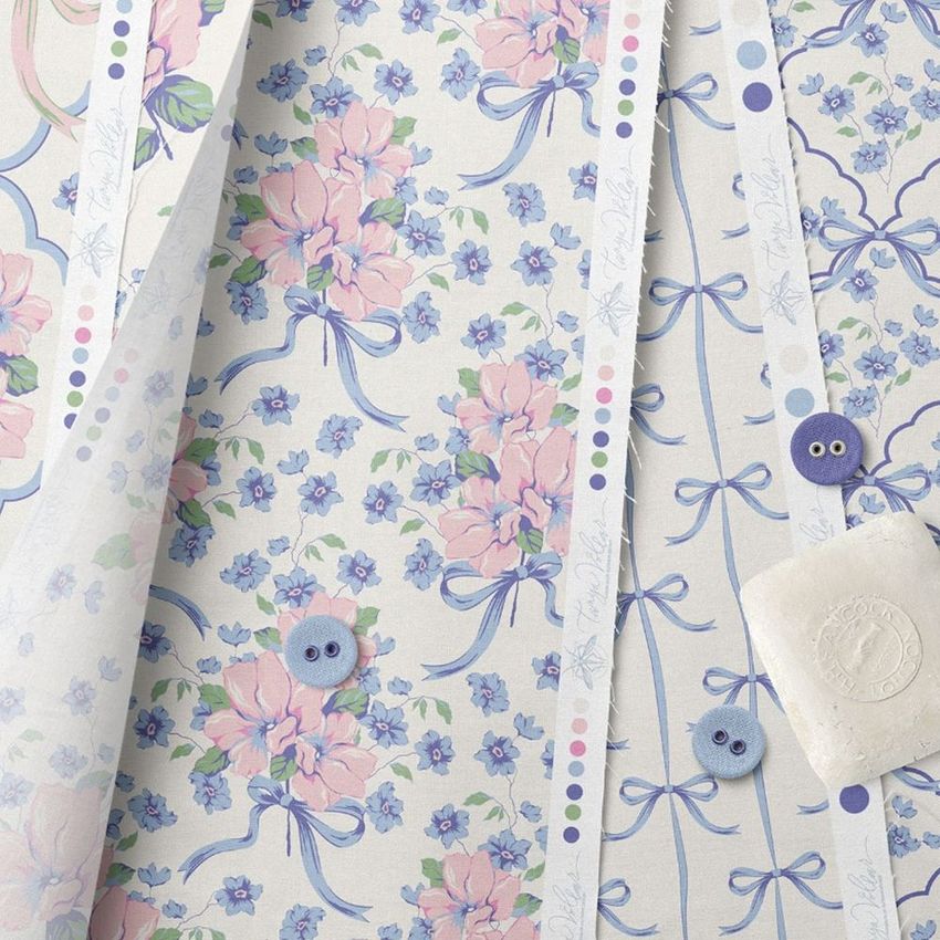 Fanned cotton fabric stack mockup displaying multiple fabric sheets with pastel floral patterns, blue buttons, and a white soap bar.