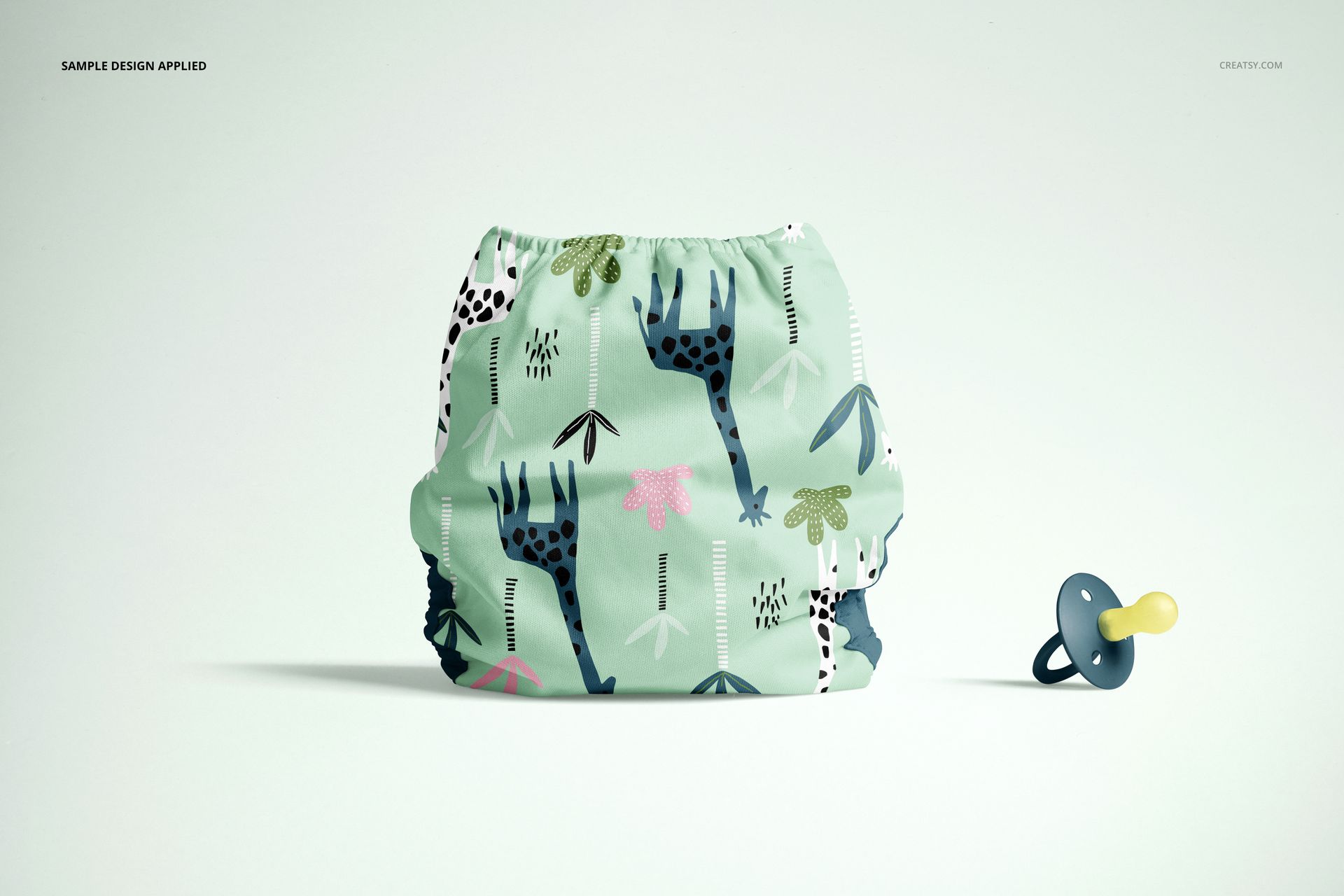 Front-facing mockup of a baby cloth diaper featuring playful giraffe and leaf designs, displayed beside a pacifier.