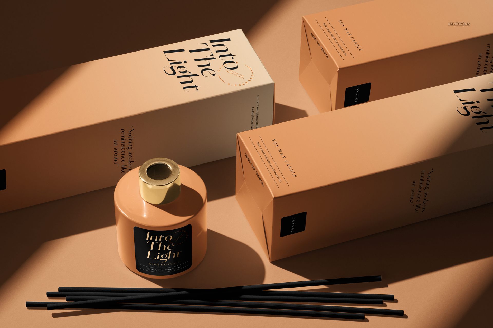 Painted glass reed diffuser mockup with black sticks and beige packaging, arranged on a tan background in sunlight.