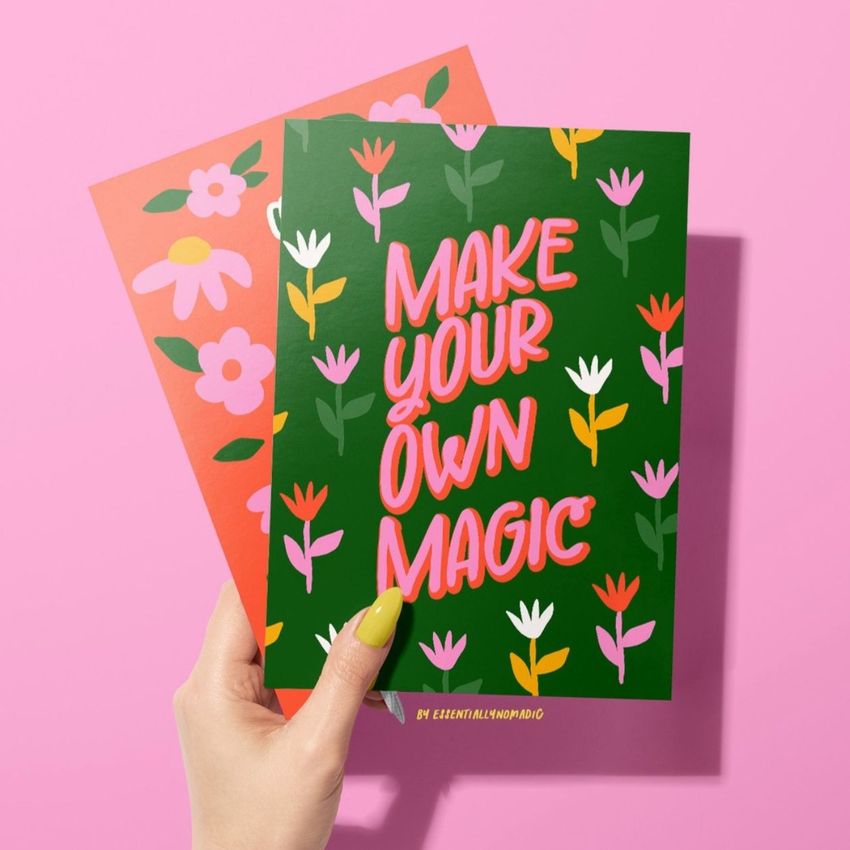 Greeting cards mockup featuring a woman's hand holding a green card with colorful floral patterns and bold text on a pink background.