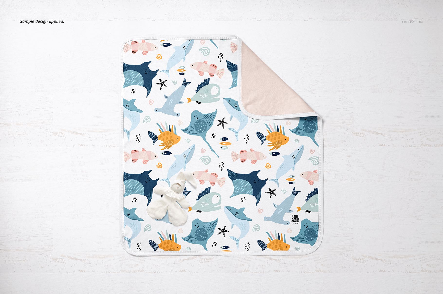 Top view of a cotton baby blanket mockup featuring playful aquatic animal illustrations and a beige reverse side.