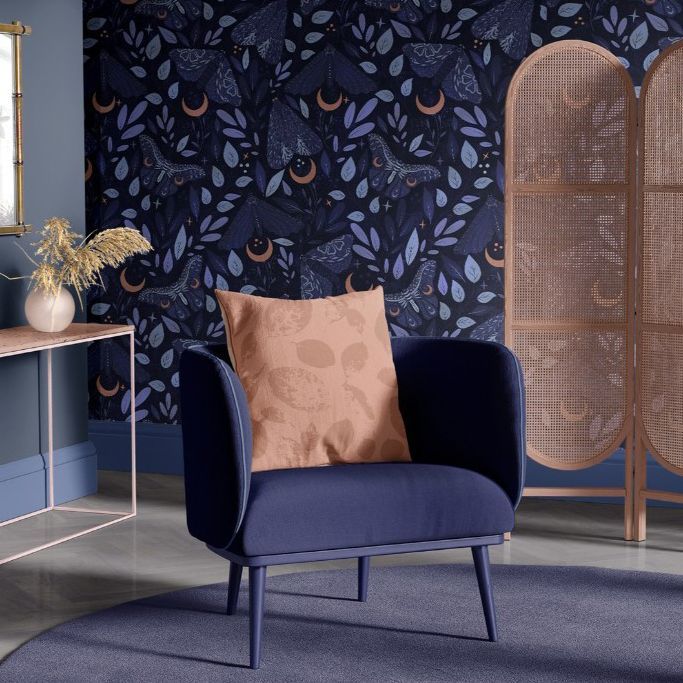Armchair mockup in a sitting corner with a dark blue moth-patterned wallpaper, a wooden screen, and a round rug.