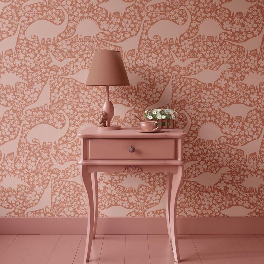 Classic console mockup featuring a pink side table with a matching lamp and small flowers, set against dinosaur-patterned wallpaper.