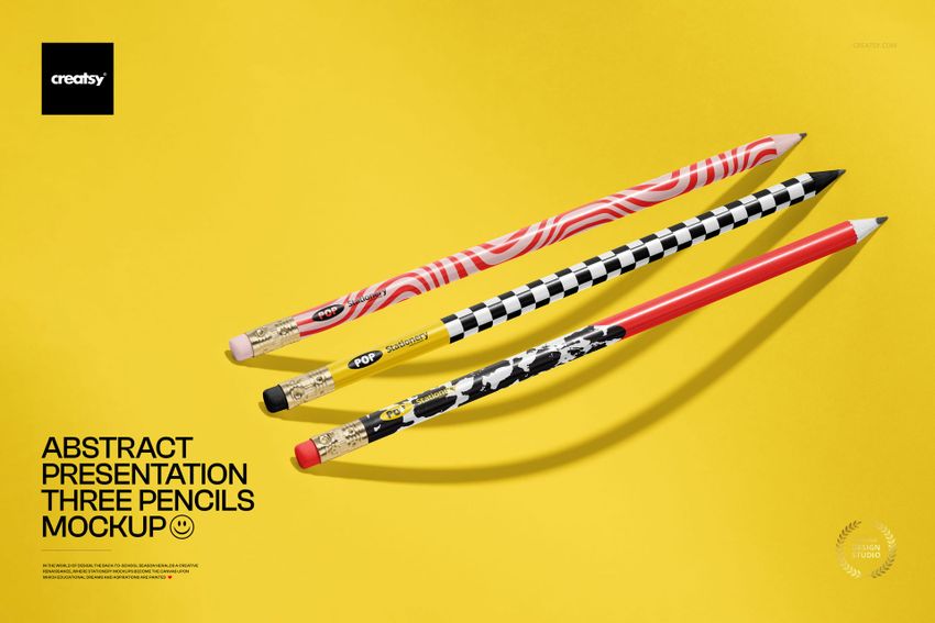 Three pencils with abstract patterns and bold colors arranged diagonally on a yellow background in a stationery mockup.