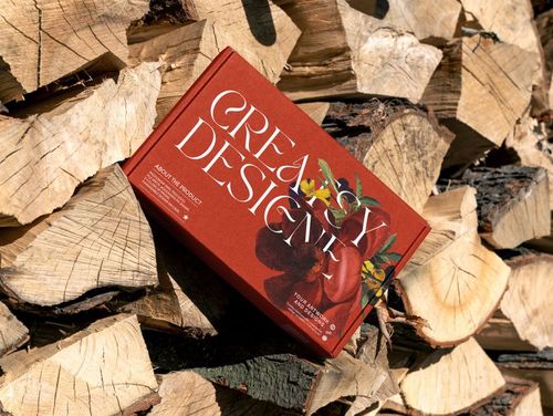 Red mailing box mockup featuring white typography and fruit graphics, displayed on chopped wood outdoors.