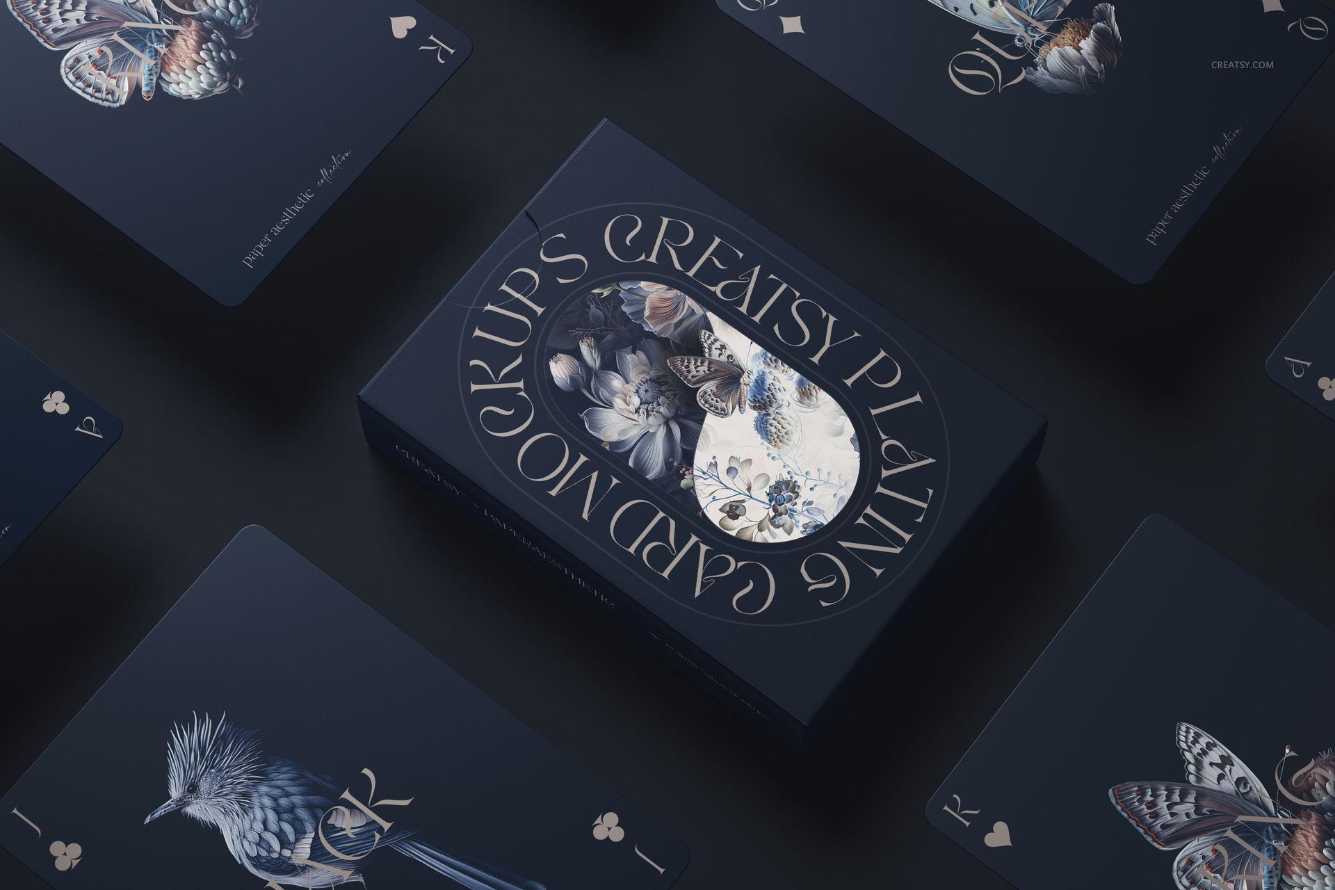 Top view of a playing cards mockup bundle featuring dark blue cards and box with bird illustrations and gold accents.