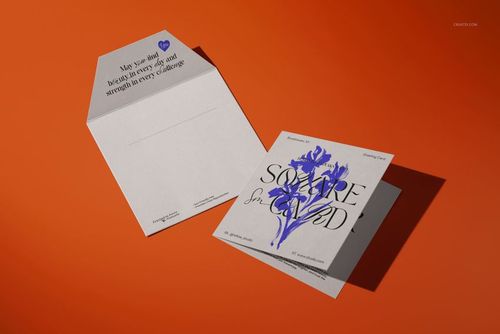Square greeting card and matching envelope mockup set on an orange surface, featuring floral graphics and text.