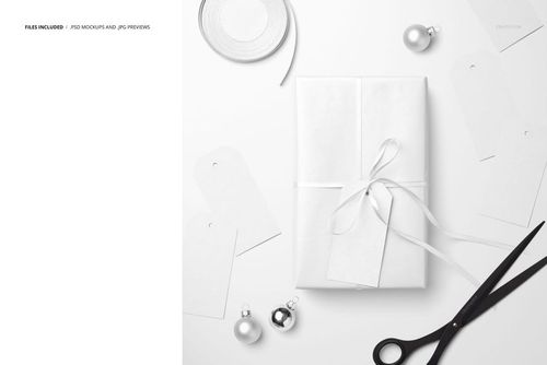 Christmas gift mockup featuring a white box with ribbon, paper labels, metallic baubles, and scissors on a table.