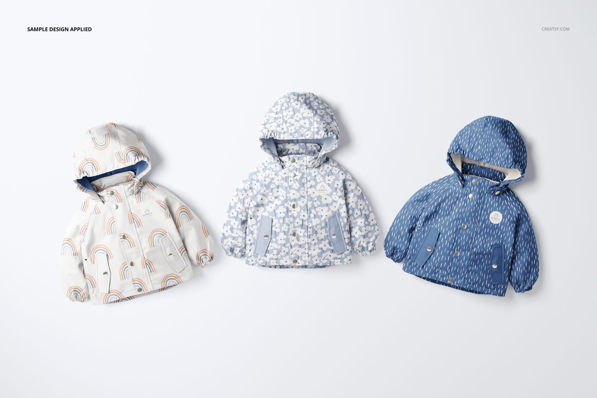 Kids rainwear PSD mockup set showing three hooded jackets in varied blue and cream colors, arranged side by side.