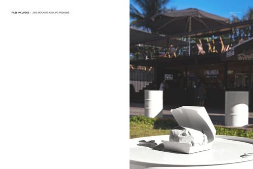White burger box mockup displayed on a round barrel table outdoors, with a food spot and palm trees in the background.