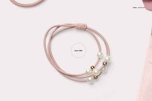 Pink elastic hair tie with multiple strands, decorated with white and gold beads, displayed on a light background.