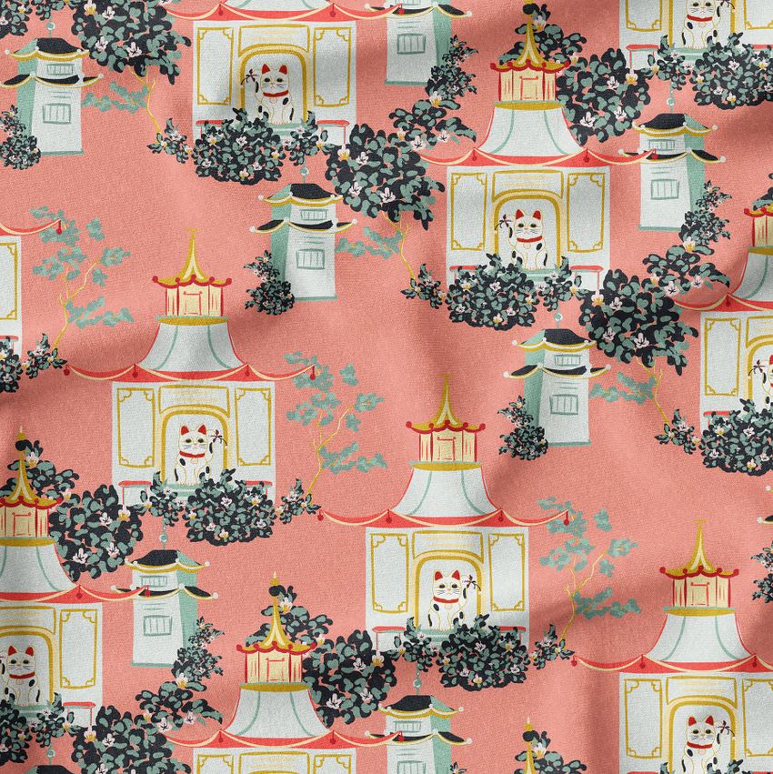 Creased fabric mockup featuring a repeating pattern of stylized pagodas and foliage on a coral pink background, viewed from above.