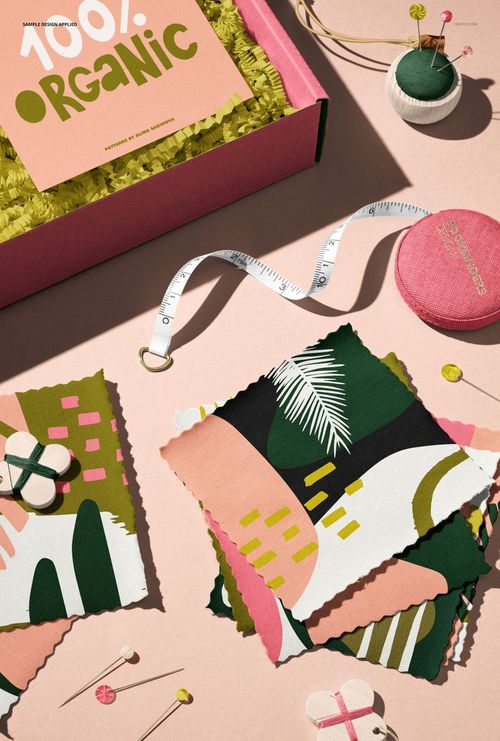 PSD mockup showing a mailing box and assorted jersey fabric swatches with colorful geometric designs and sewing props.