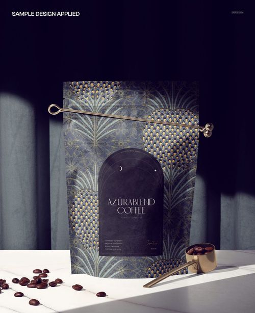 Front view of a coffee pouch mockup with intricate gold and navy design, placed beside a metal scoop and coffee beans.
