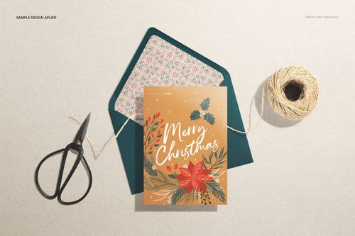 Stationery mockup featuring a holiday card with floral design, matching envelope, scissors, and twine on a neutral surface.