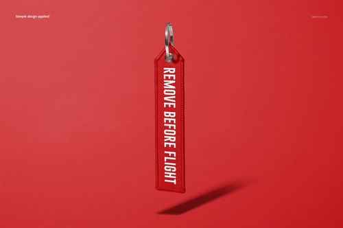 Mockup of a red 'Remove Before Flight' keychain, showing stitched edges and metal ring, centered on a plain red surface.