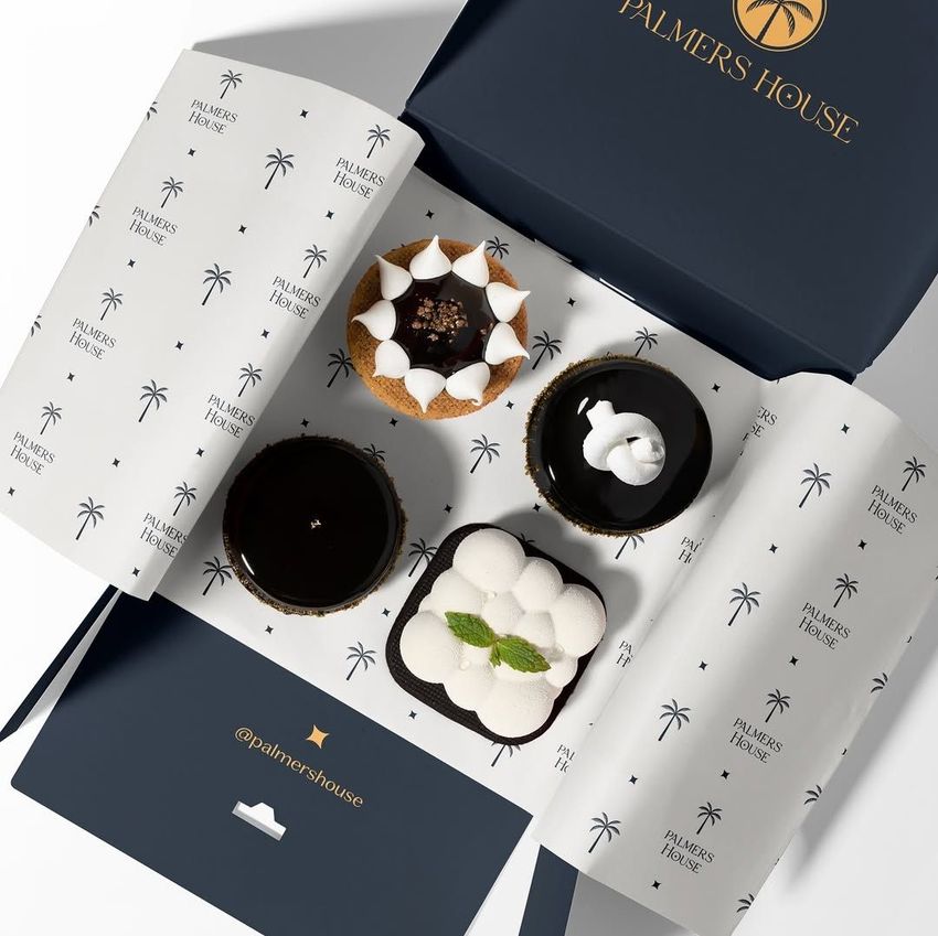 Food safe paper mockup featuring a dessert box partially wrapped in white paper with black palm tree patterns and visible text.