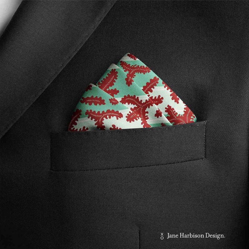Pocket square mockup featuring a folded fabric with a red and green abstract pattern in the pocket of a black suit jacket.