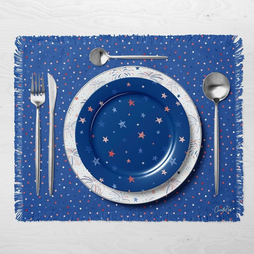 Tableware mockup showing a blue fringed placemat with white and red dots, a blue plate with star patterns, and silver cutlery.