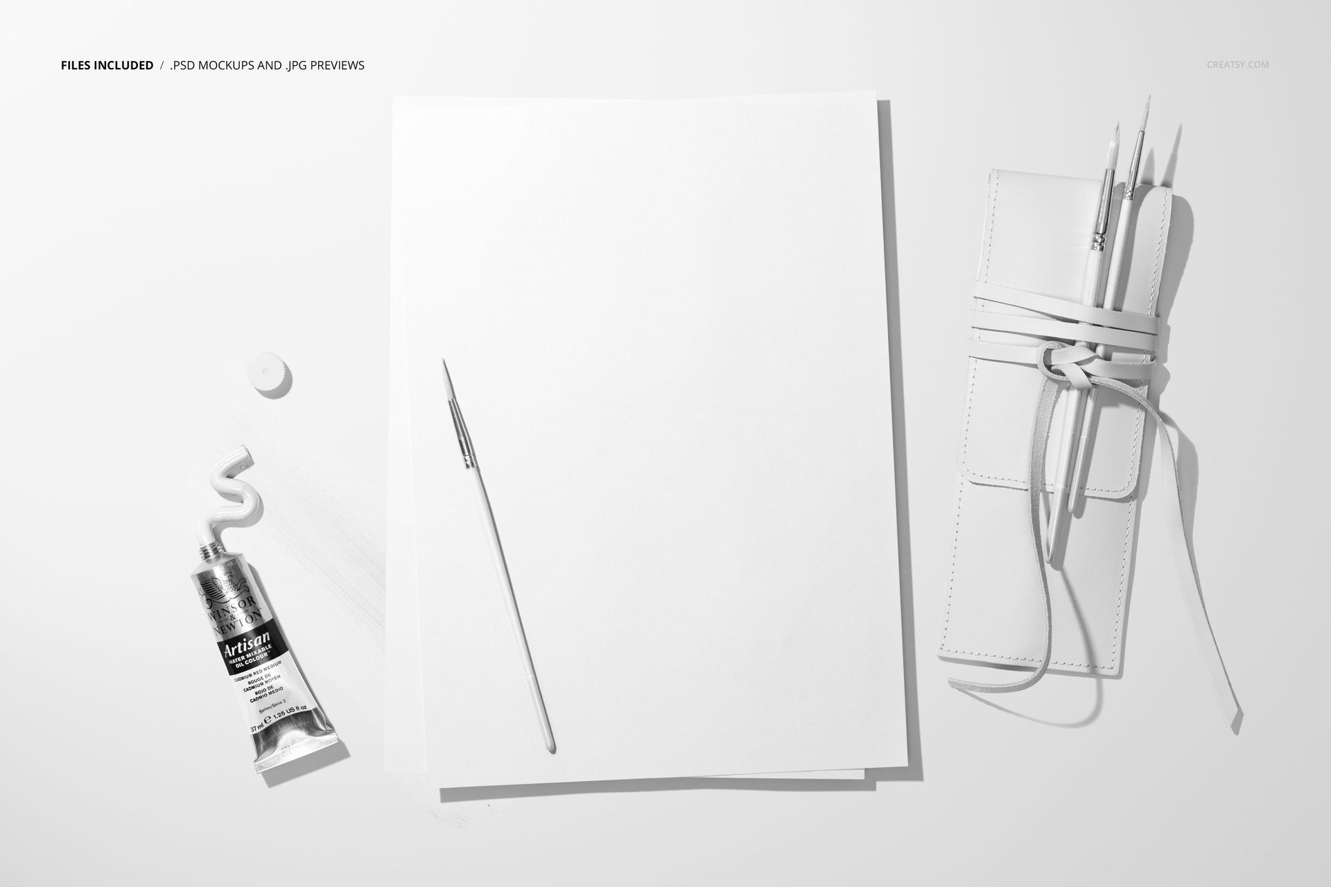 Art paper mockup with painting supplies including a paint tube, palette knife, and brush case arranged neatly.