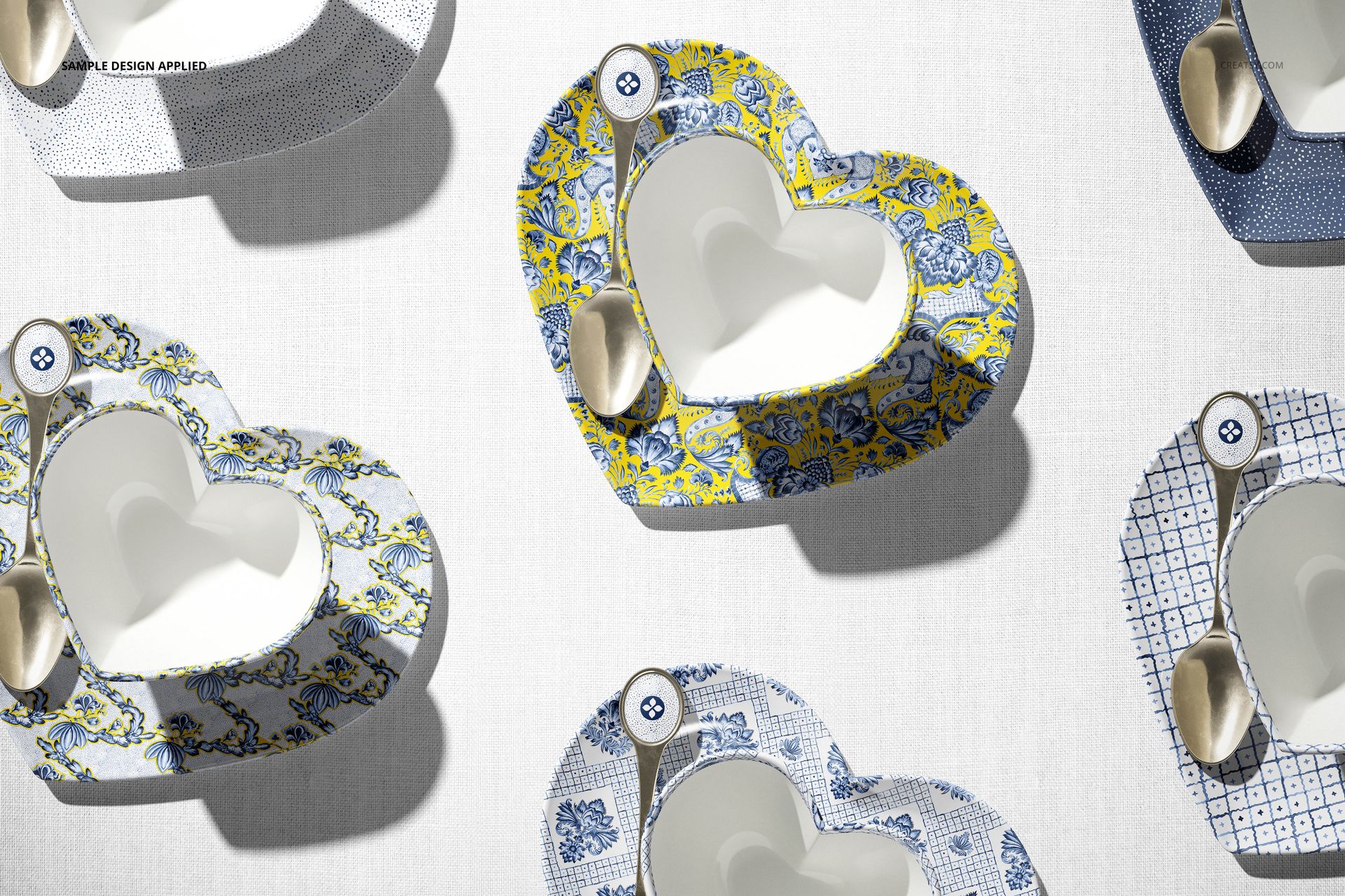 Top view of heart-shaped cup mockup set with patterned saucers and metallic spoons on a neutral background.
