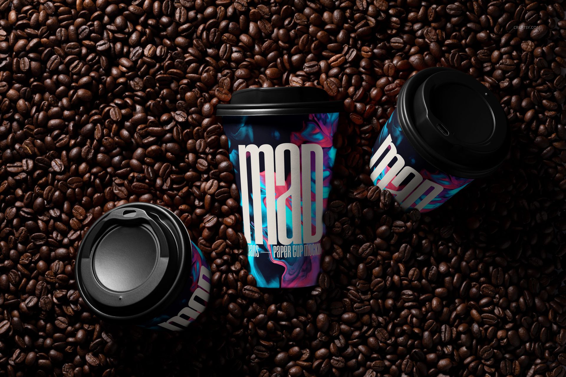 PSD mockup of paper cups with vibrant patterns and black lids displayed among scattered coffee beans, viewed from above.