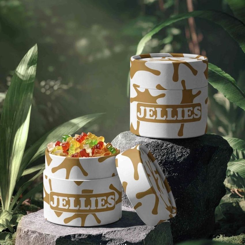 Paper tube packaging mockup with a jungle jellies design, featuring colorful gummy candies and bold text on white containers outdoors.