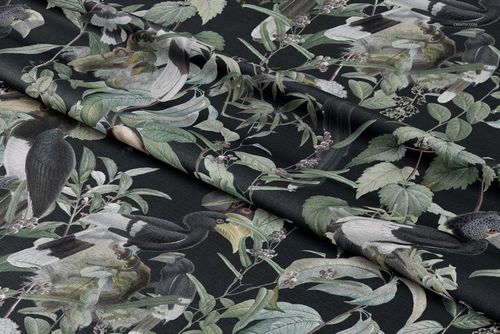 Folded tablecloth fabric mockup with illustrated birds and green foliage on a dark background, viewed from above.