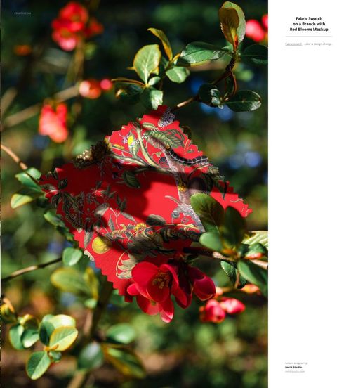 PSD mockup of a decorative red fabric sample with botanical and bird motifs set outdoors among fresh green leaves.