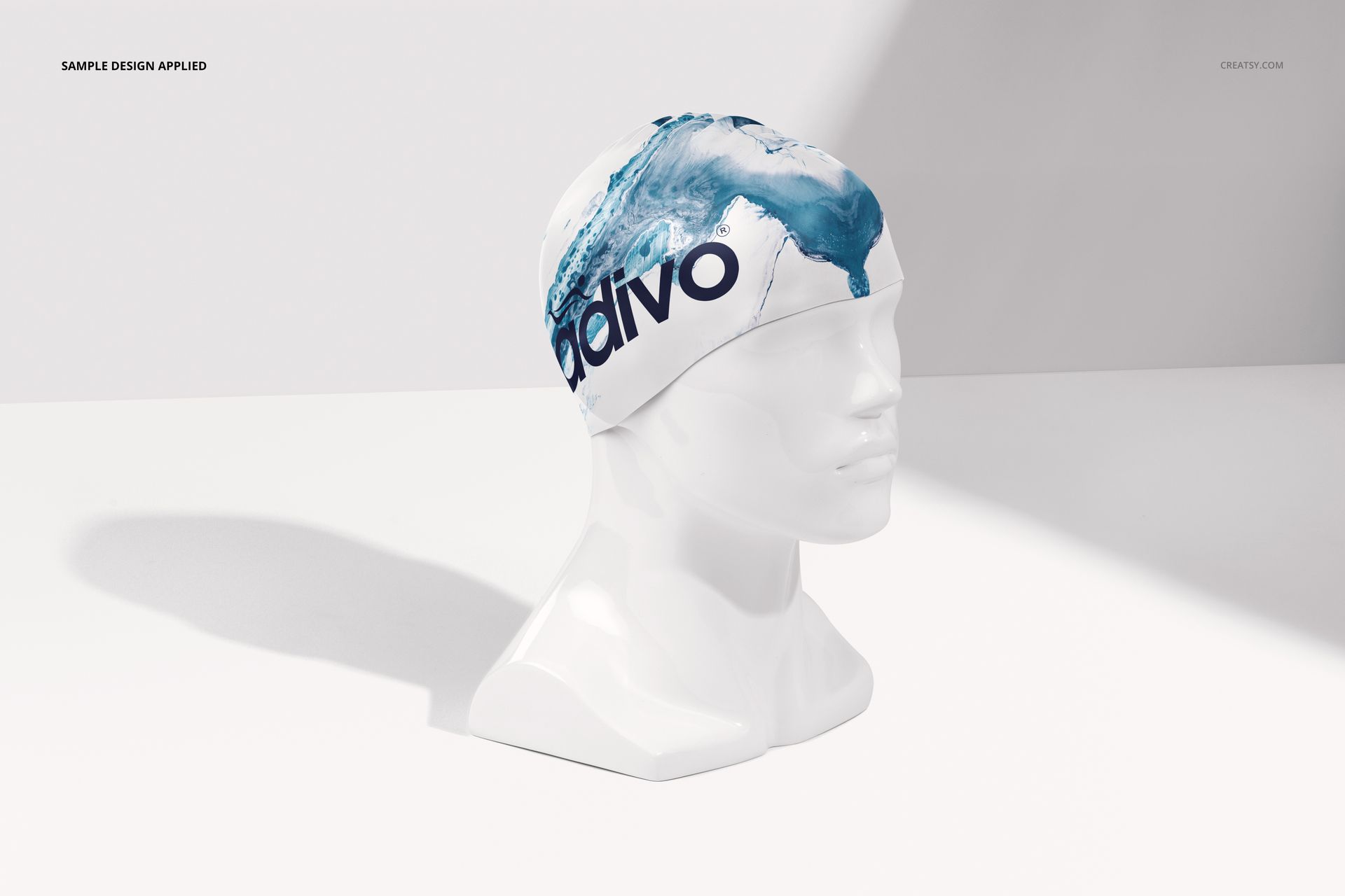 Swim cap mockup featuring a blue water splash design on a white cap, displayed on a white mannequin head in a bright studio setting.