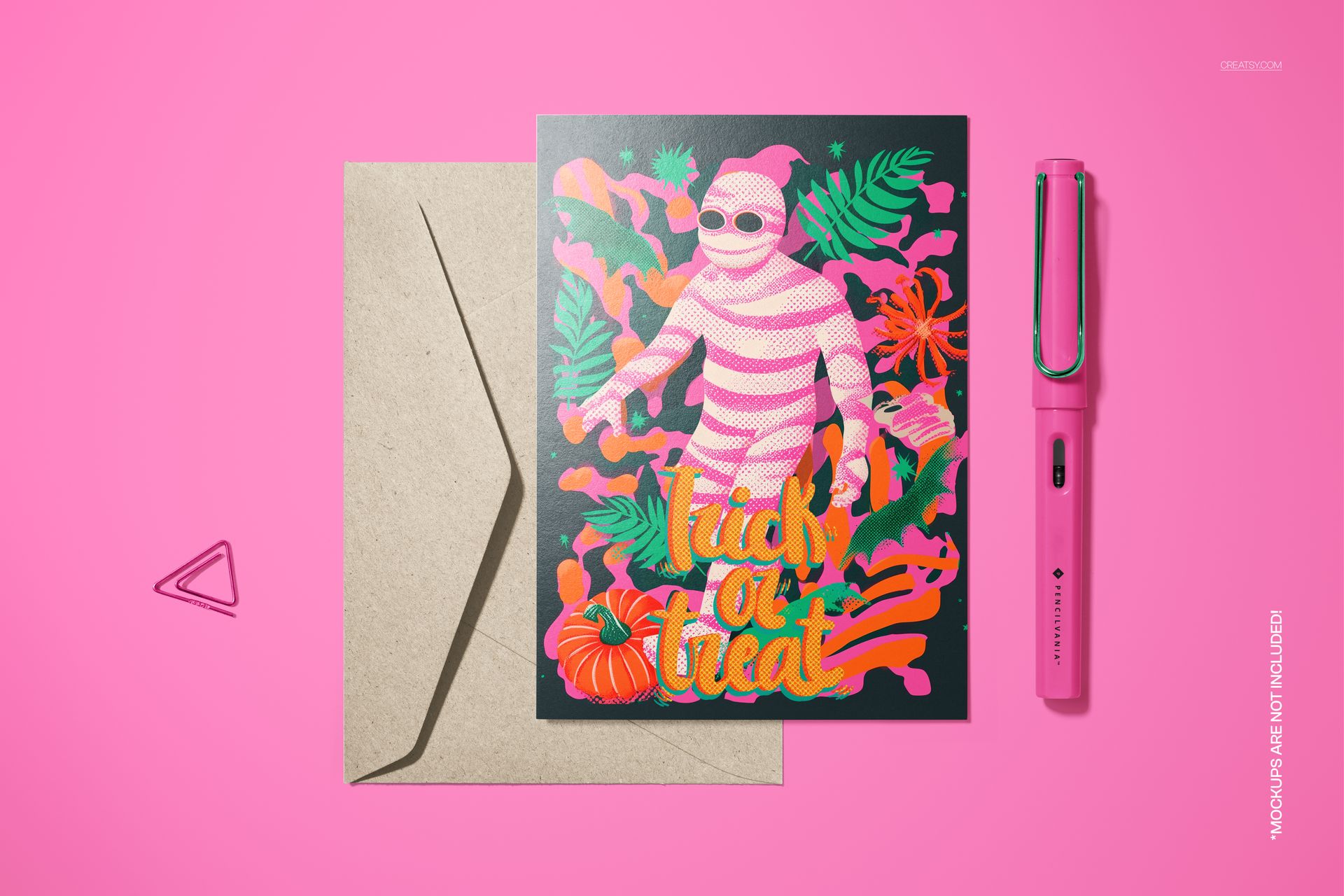 Halloween 5x7 card mockup with a creepy striped mummy design, pumpkin accents, kraft envelope, and pink pen on a pink surface.