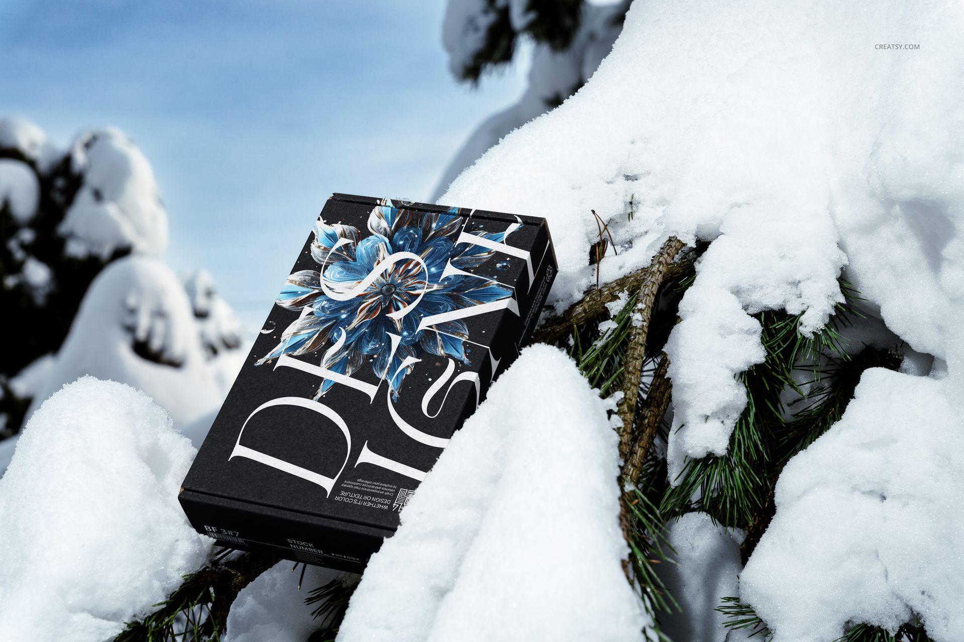 Winter edition mailing box mockup featuring dark packaging with large white letters, set among snowy tree branches.