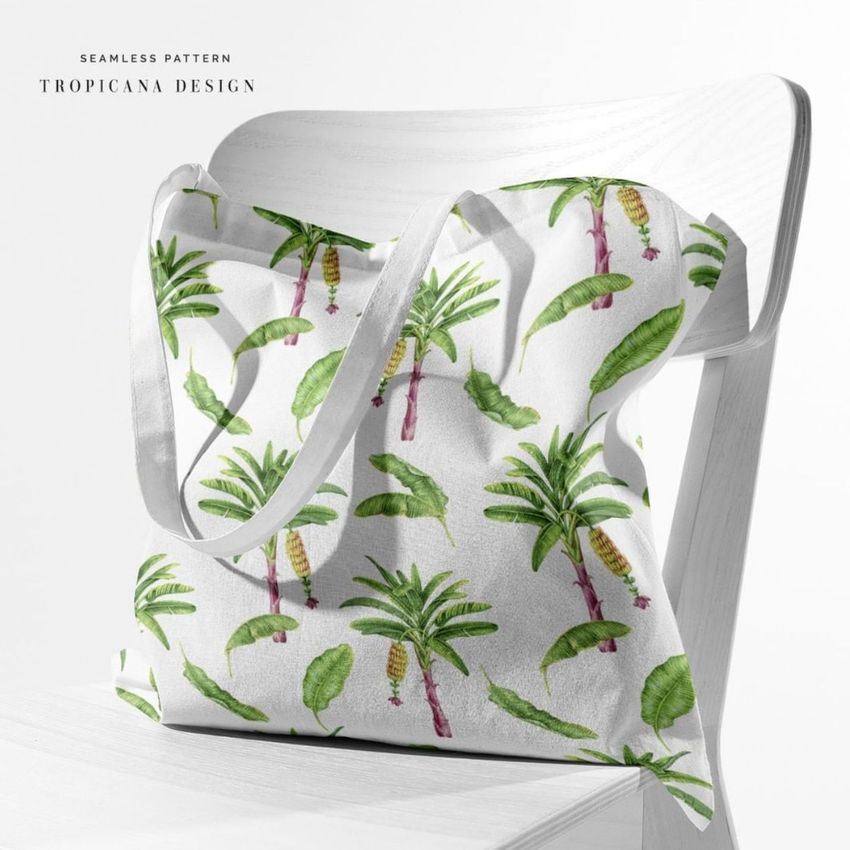 Tote bag mockup displayed on a white chair, featuring a seamless tropical pattern with green palm trees and leaves.