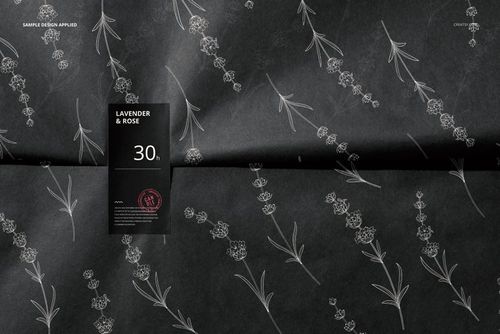 Front view of dark wrapping paper featuring thin white botanical designs, accompanied by a black sticker mockup.