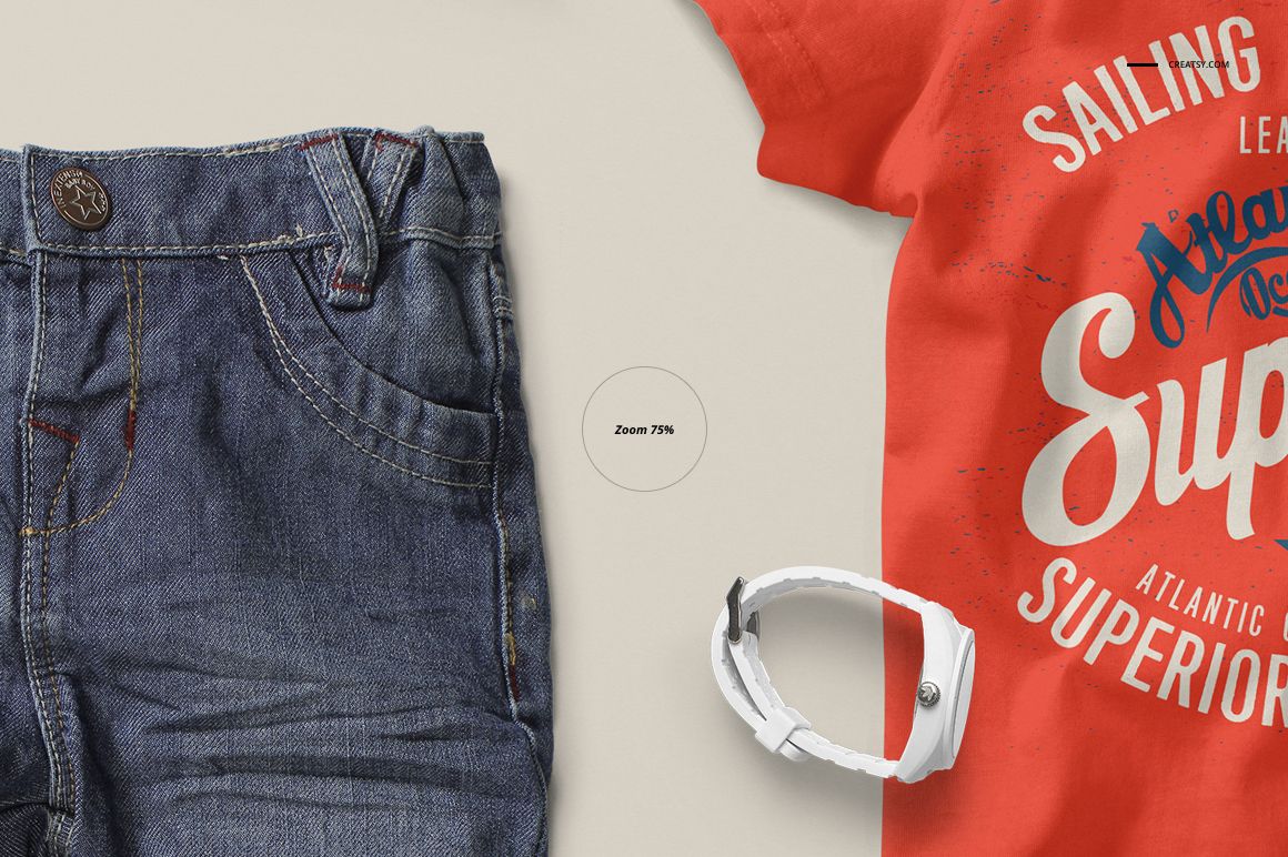 Front view of a baby t-shirt mockup in bright orange with white printed text, next to denim jeans and a white wristband.