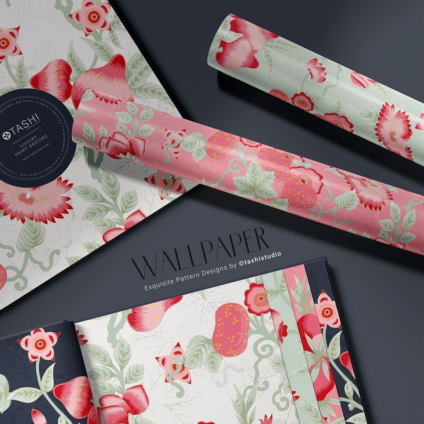 Wallpaper sample book mockup featuring floral patterned pages in pink, green, and cream, with two rolled wallpaper sheets on a dark surface.
