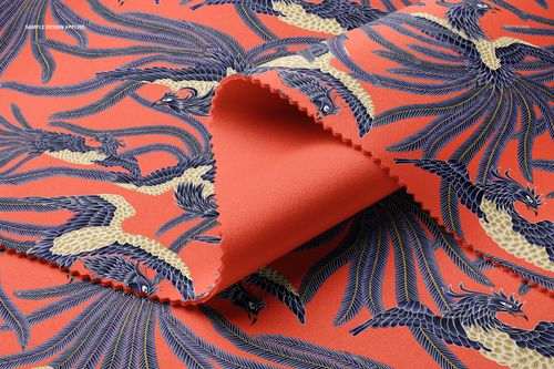 Scuba fabric mockup featuring folded textile with a bold orange background and intricate blue and cream bird pattern.