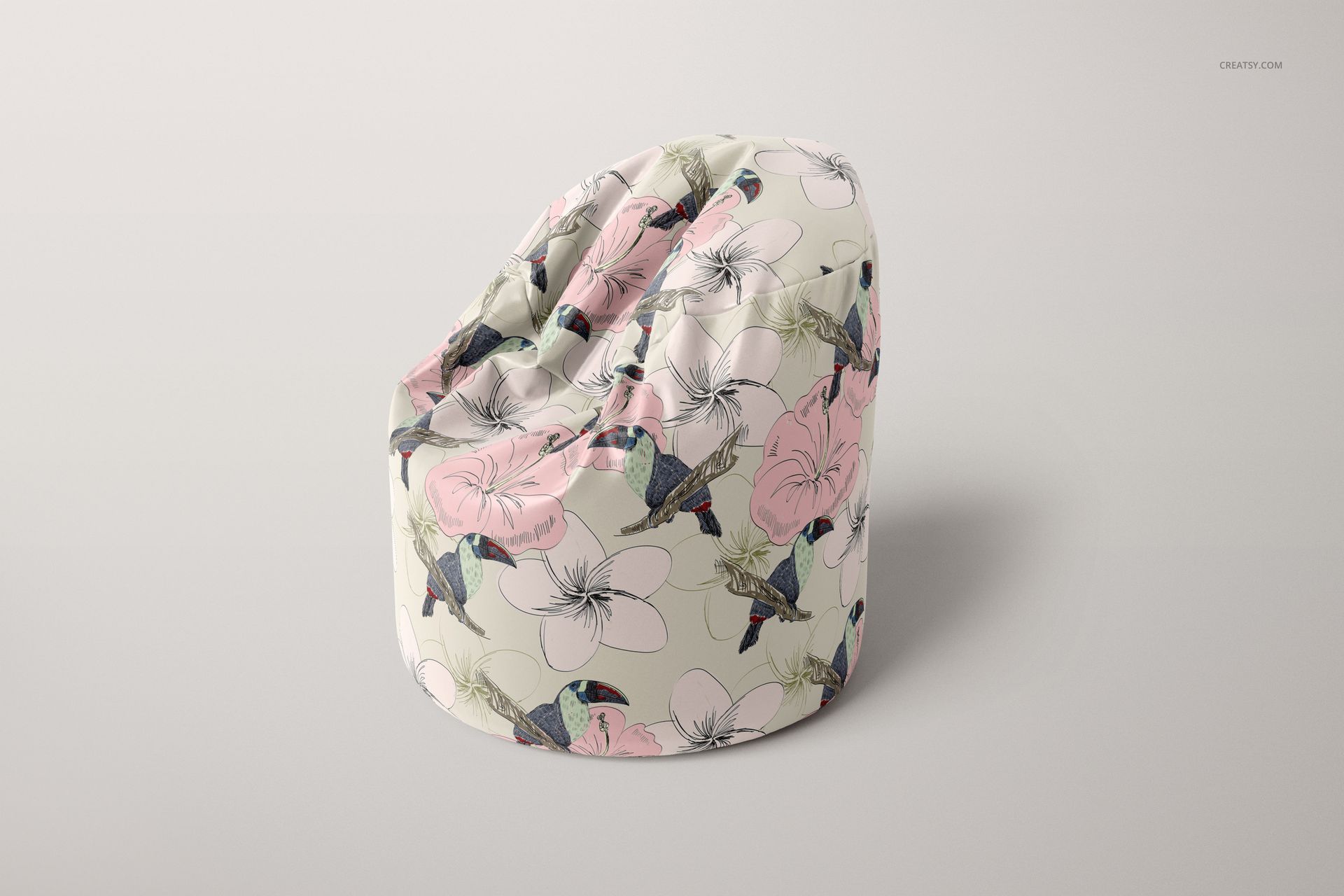 PSD mockup of a bean bag chair featuring large pink flowers and hummingbirds, displayed on a neutral surface.