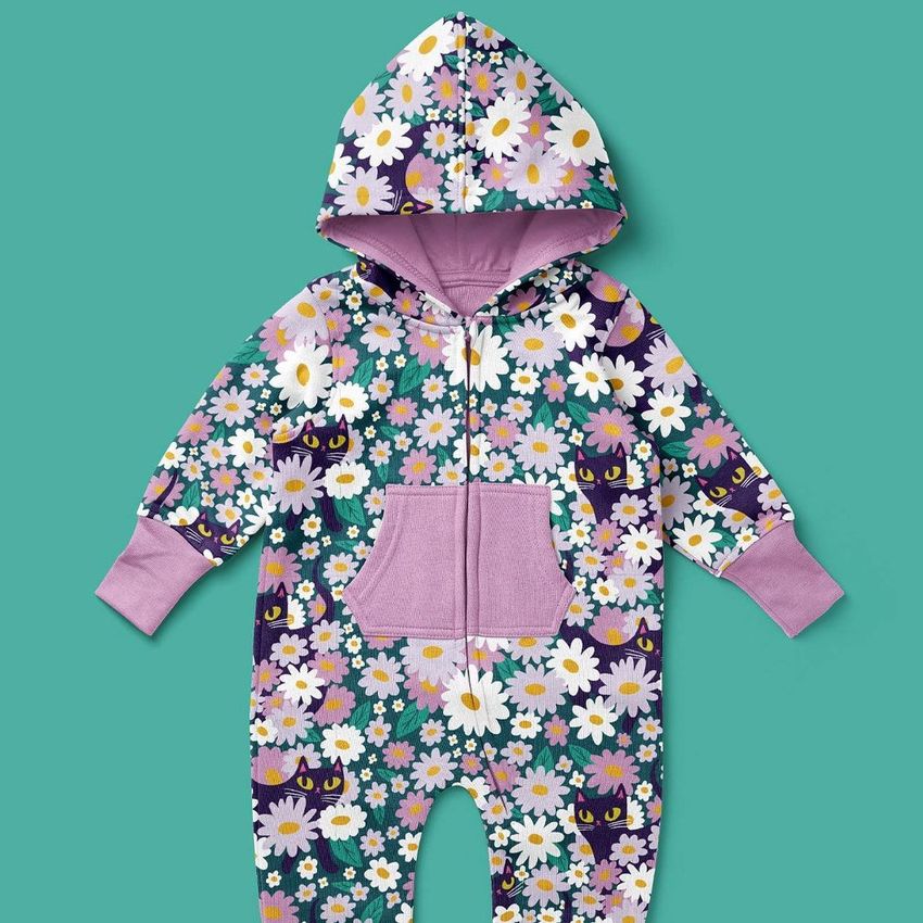 Baby fleece onesie mockup with a hood, featuring a playful pattern of black cats and colorful flowers on a teal background.