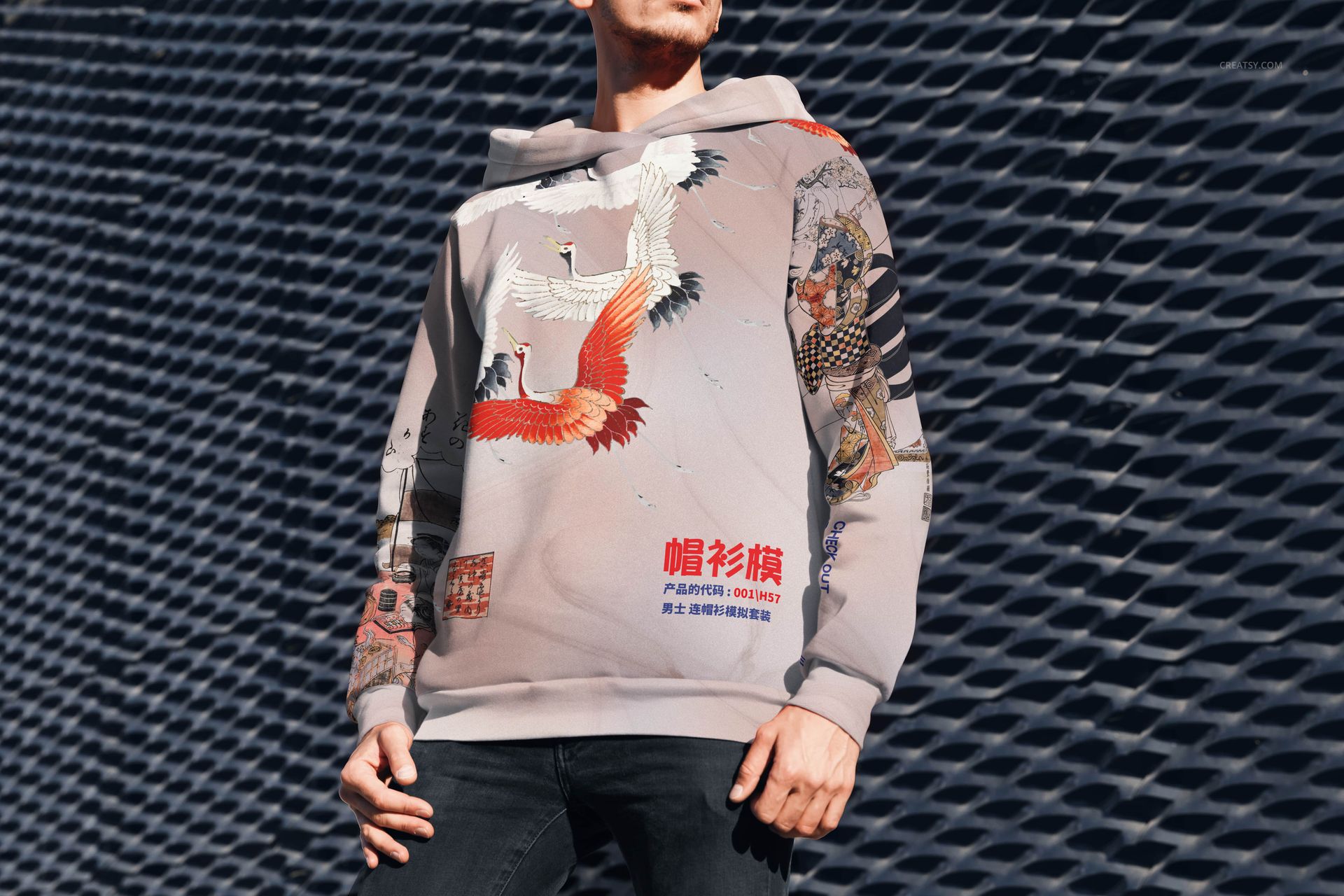 PSD mockup of oversized hoodie with colorful crane and graphic elements, modeled outside near a geometric background.