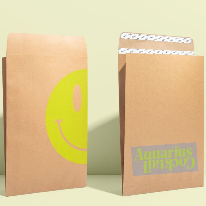 Kraft mailer mockup featuring two brown paper envelopes, one with a large yellow smiley face and the other with text on the flap, set against a light background.