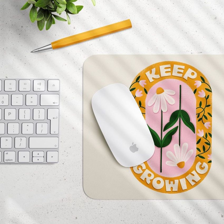 Rectangular mouse pad mockup with a floral pattern and the words 'Keep Growing', shown on a desk with a white mouse and keyboard.