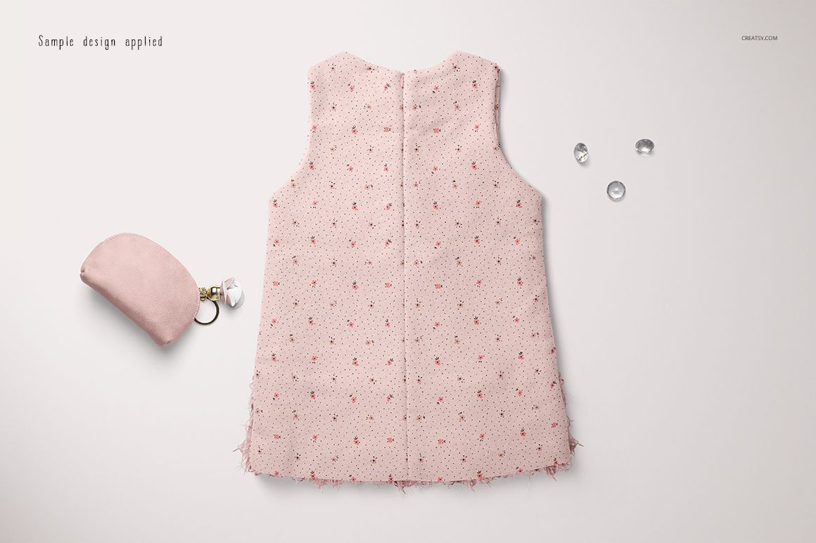 Sleeveless baby dress mockup in pale pink with small red floral pattern, displayed flat on a light background.