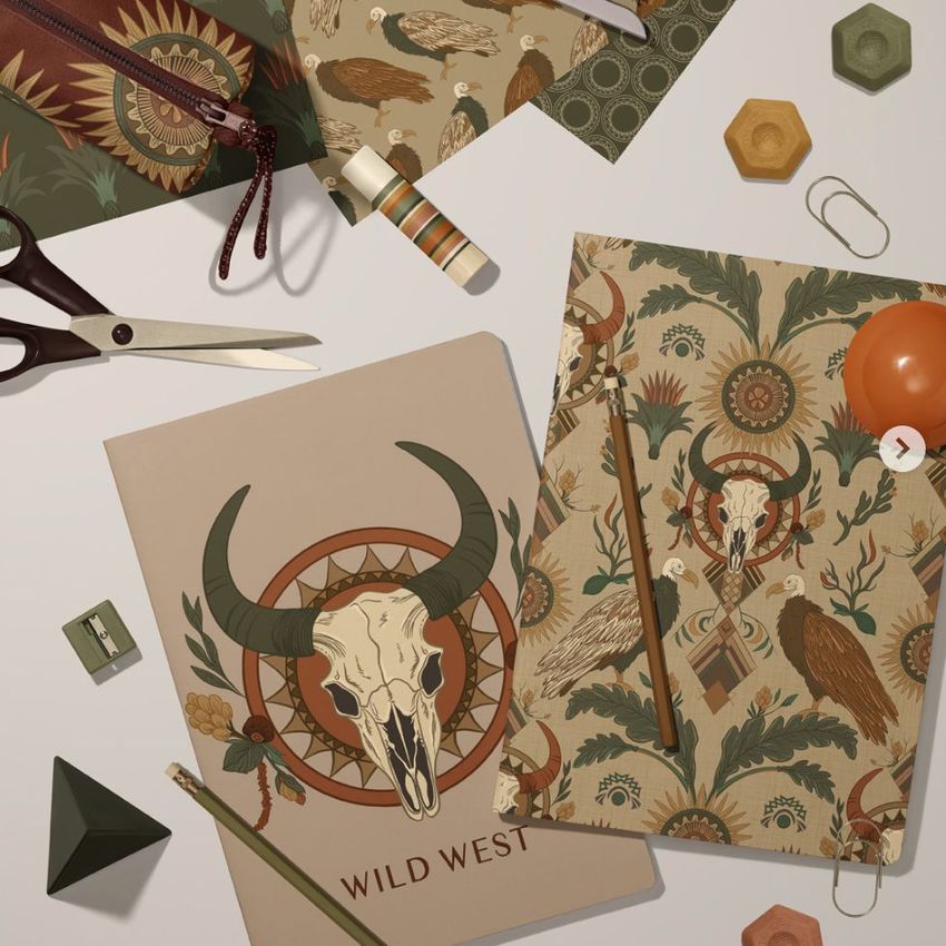Stationery mockup featuring two classic A4 notebooks with Wild West-themed covers, surrounded by office supplies on a light surface.