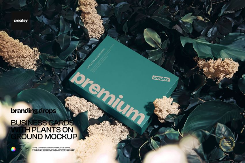 PSD mockup of a teal packaging box placed among lush green foliage and clusters of pale flowers, viewed from above.