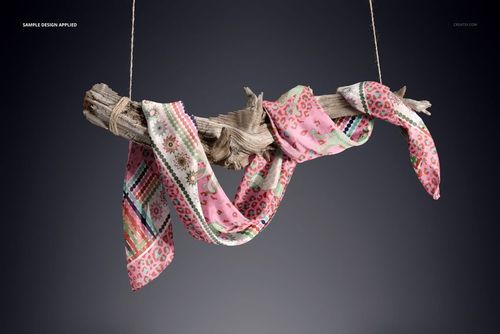 PSD mockup of a patterned silk scarf hanging loosely on driftwood, showing detailed hand-rolled edges and textures.