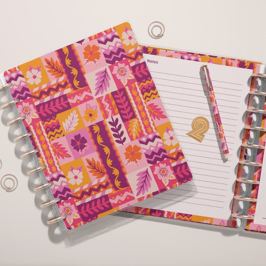 Two spiral-bound planner mockups with vibrant floral and abstract patterns, one open to a lined notes page with a matching pen.